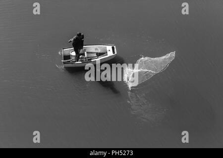 Fischer casting net Aktion, um die Fischerei mit kleinen Boot in Fluss Wasser der Lagune overhead Foto Stockfoto