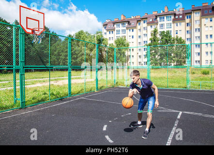 Junger Mann spielen Basketball im Freien an einem sonnigen Sommertag Stockfoto
