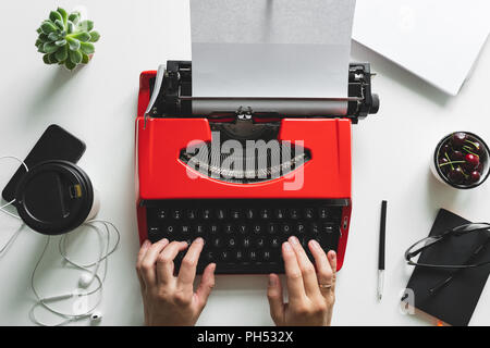 Frau wird das Arbeiten mit leuchtend roten vintage Schreibmaschine Stockfoto