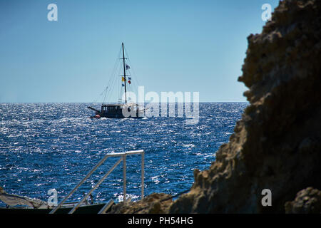 Ein Schiff, ein Boot auf dem Weg zum Hafen auf einem Meer mit klarem und blauem Wasser in Erinnerungen gefangen Stockfoto