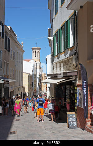 Spanien. Balearen, Menorca, Mahon. Stadtzentrum. Schmale Straße mit Fußgängern und die Kathedrale von Santa Maria Bell Tower im Hintergrund. Stockfoto