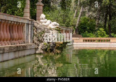 White Skulptur von zwei Delphinen mit verschlungenen Schwänzen am Teich in Horta Labyrinth Park. Die Skulptur ist aus Marmor auf der Basis von Steingarten. Stockfoto