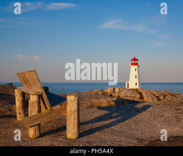 Holzbank mit Peggy's Cove Leuchtturm im Hintergrund an sonnigen Morgen. Stockfoto