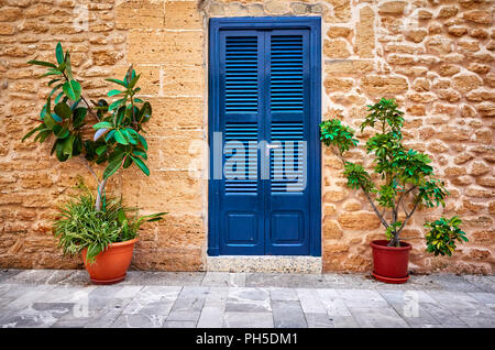 Alte Steinmauer mit blauer Tür und Blumentöpfe, Mallorca, Balearen, Spanien. Stockfoto