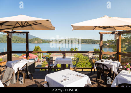 Ein Restaurant Terrasse mit Tischen mit Blick auf Gibsons, BC, an einem hellen, sonnigen Tag. Stockfoto