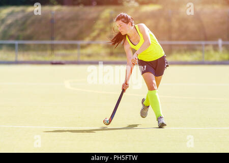 Jungen Hockeyspieler Frau mit Ball im Angriff spielen Hockey Game Stockfoto