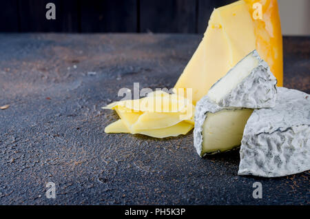 Verschiedene Arten von Käse auf dem Brett, Käseplatte aus einem Stück harten Käse, dünne Scheiben geschnitten, runden blauen Käse Kopf Stockfoto