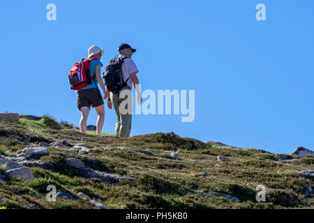 Vater und Tochter mit Rucksäcken zu Fuß auf den Berg weg im Frühjahr/Sommer im Cairngorms Nationalpark, Highland, Schottland, UK Stockfoto