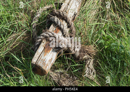 Verschlissene und beschädigte nautische Seil um ein verrottendes Holz- Post am Flussufer bei Skippool Creek in der Nähe von Poulton-le-Fylde, Lancashire, England, Großbritannien Stockfoto