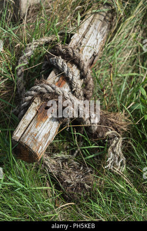 Verschlissene und beschädigte nautische Seil um ein verrottendes Holz- Post am Flussufer bei Skippool Creek in der Nähe von Poulton-le-Fylde, Lancashire, England, Großbritannien Stockfoto