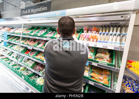 CoOp Lebensmittel Shop. Ein männlicher Arbeitnehmer Stapeln Regale Stockfoto