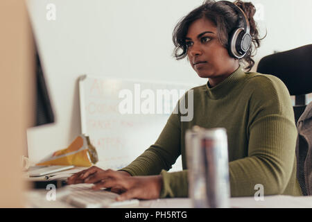 Programmiererin in einer Software arbeiten, die Entwicklung von Unternehmen. Frau mit Kopfhörern Codierung auf dem Desktop Computer. Stockfoto