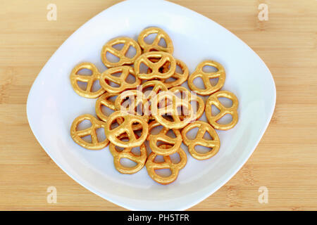 Eine Platte mit Gold bemalt Brezeln ruht auf einem Holztisch. Stockfoto