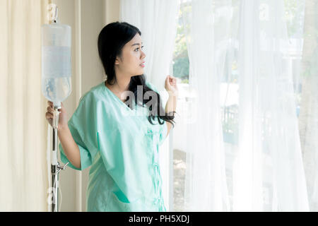 Asiatische Patienten Frau suchen draußen vor dem Fenster, Patienten froh ist von der Krankheit erholt. Stockfoto