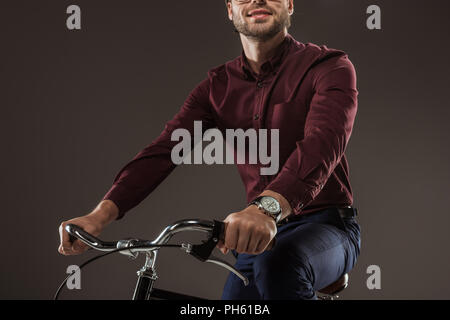 7/8 Schuß von lächelnden Mann reiten Fahrrad auf Schwarz Stockfoto