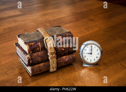 Drei Schulbücher mit einem alten Gürtel auf einem Schreibtisch mit einer Vintage-Uhr, Stillleben, USA, Schulbücher Schreibtisch historische Bilder amerikanisch Stockfoto