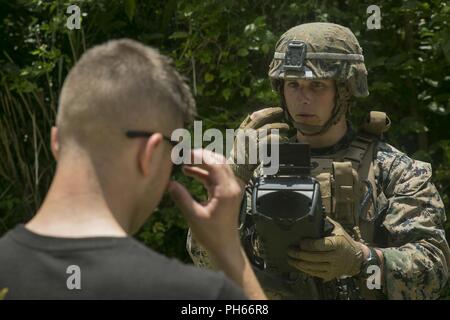 Lance Cpl. Gavin Weiß, eine militärische Polizist mit der Bekämpfung der Logistik Bataillon 31 und New Orleans, Louisiana Eingeborener, fragt eine Rolle Spieler seine Sonnenbrille während eine humanitäre Hilfe - Katastrophenhilfe Übung als Teil des 31 Marine Expeditionary Unit MEU Übung in Kin Blau, Okinawa, Japan, 27. Juni 2018 zu entfernen. MEUEX ist das erste in einer Reihe von vor der Bereitstellung Schulungen, die Vorbereitung der 31. MEU kurzfristig bereitstellen. Die 31. MEU, das Marine Corps' nur kontinuierlich vorwärts - bereitgestellt MEU, bietet eine flexible Kraft bereit, eine breite Palette von militärischen Operationen auszuführen. Stockfoto