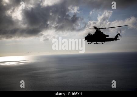 Ein U.S. Marine Corps AH-1Z Viper Hubschrauber Marine Light Attack Helicopter Squadron 469, Marine Flugzeuge Gruppe 39, 3. Marine Flugzeugflügel zugeordnet, unter der Anlage Deployment Program mit MAG-36, 1 MAW fliegt über Okinawa, Japan, nach Durchführung einer live Brand, 27. Juni 2018. Die Durchführung von Live Fire Training ist entscheidend die Effizienz und Stärke zu erhalten. Stockfoto