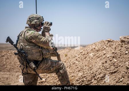 Ein US-Soldat mit Fernglas in Richtung der Demarkationslinie in der Nähe von einem Dorf außerhalb Manbij, Syrien, 26. Juni 2018 zu sehen. Die Patrouillen werden in Abstimmung mit der türkischen Streitkräfte, die Patrouille auf der gegenüberliegenden Seite der Leitung, die Sicherheit und die Sicherheit in der Region zu erhalten, da es von ISIS befreit wurde. Stockfoto