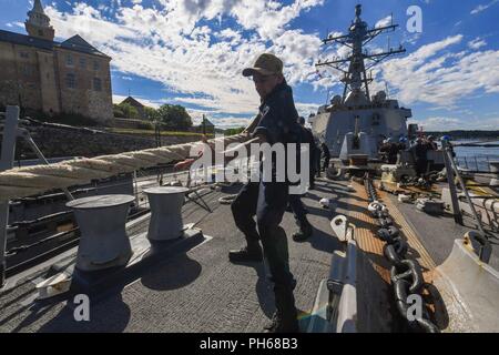 Norwegen (26. Juni 2018) Kulinarische Specialist 3. Klasse Adrian Bradford wuchtet eine Linie als der Arleigh-Burke-Klasse geführte Anti-raketen-Zerstörer USS Bainbridge (DDG96), Abfahrt Oslo, Norwegen, nach einem geplanten Hafen besuchen Sie am 26. Juni 2018. Bainbridge, homeported in der Naval Station Norfolk, ist die Durchführung von naval Operations in den USA 6 Flotte Bereich der Maßnahmen zur Unterstützung der US-amerikanischen nationalen Sicherheitsinteressen in Europa und Afrika. Stockfoto