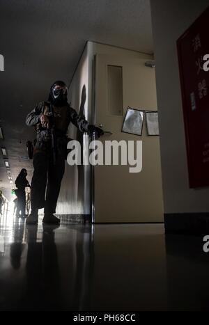 Ein U.S. Marine Corps Marine aus der Provost Marshal Office spezielle Reaktion Team bewacht den Eingang der ein Zimmer während eines aktiven shooter Training Juni 25, 2018, an der Ryukyu Middle School, Kadena Air Base, Japan. Die Übung aktiviert 18 Sicherheitskräfte Squadron Verteidiger mit einem US Marine Corps spezielle Reaktion Team und die kadena Feuerwehr ihre Fähigkeiten zu verbessern, zu arbeiten. Stockfoto