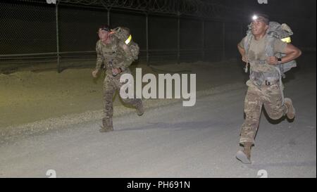 Us-Armee SPC. Austin Mellon, Links, eine Kavallerie Scout zu Charlie Truppe, 1. Der 124. Kavallerie, US-Army Central zugeordnet, und die US-amerikanische Armee SPC. Joselito Reyes, ein radfahrzeug Mechaniker Charlie Batterie, 5. Der 52. Air Defense Artillery Battalion, USARCENT, Kampf für eine Leitung über einander während der Ruck März an USARCENT's Best Krieger Wettbewerb im Camp Arifjan, Kuwait, 28. Juni 2018 vergeben. Ruck Märsche bieten Soldaten mit einer Gelegenheit, sich gegen ihre Altersgenossen zu testen und der Zusammenhalt zwischen den konkurrierenden Einheiten stärken. Stockfoto