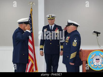 Coast Guard Master Chief Petty Officer Christopher Wright, Offizier der Station Hatteras Inlet in Hatteras, North Carolina, begrüßt Senior Chief Petty Officer James Pond, sein Nachfolger, während der Change-of-Befehl Zeremonie, Juni 29, 2018 der Station. Kapitän Bion Stewart, Commander, Sektor Nord Carolina, den Vorsitz über die Zeremonie. Stockfoto