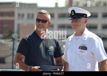 AOC Christopher Crabtree, von der USS Gerald R. Ford (CVN-78) steht mit einem Familienmitglied eine Bescheinigung der Anerkennung während seiner 57-Rekrutierung Zeremonie auf der USS Wisconsin. Die USS Wisconsin (BB-64) ist ein Iowa - Klasse Schlachtschiff, die ursprünglich im Jahr 1944 in Betrieb genommen. Da stillgelegt wird, hat neben dem Hampton Roads Naval Museum und Nauticus liegt in der Innenstadt von Norfolk, Virginia als Museumsschiff. Das Museum ist in der Lage, militärische Zeremonien, wie Re-enlistments, Promotions und Abgänge an Bord der legendären USS Wisconsin kostenlos. Interessierte Befehl Stockfoto