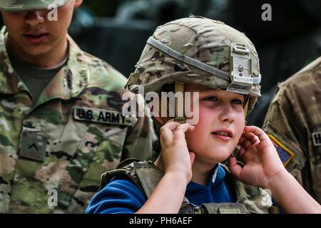 Ein Polnisches Kind auf einem Kevlar Helm aus der 1. Staffel versucht, 2.Kavallerie Regiments bei einer statischen Anzeige mit Battle Group Polen in Lötzen, Polen am 30. Juni 2018. Battle Group Polen ist ein einzigartiges, multinationale Koalition von USA, Großbritannien, Kroatischen und rumänischen Soldaten, die mit der polnischen 15 mechanisierte Brigade als Abschreckung Kraft zur Unterstützung des NATO-Enhanced vorwärts Präsenz dienen. Stockfoto