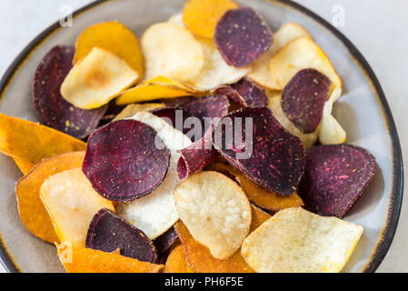 Schüssel mit gesunder Snack aus pflanzlichen Chips, wie süsse Kartoffeln, Rote Beete, Karotten, Pastinaken auf Hellgrauem Hintergrund Stockfoto