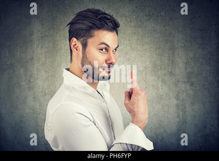Gut aussehender bärtiger Mann mit dem Finger auf die Nummer Eins auf grauem Hintergrund ironisch Stockfoto