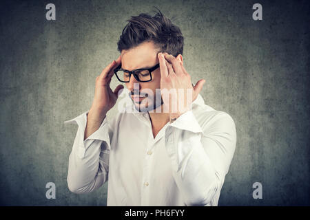 Erwachsenen Mann in Gläsern mit Fingern auf die Tempel, die versuchen, auf den Entscheidungsprozess konzentrieren. Stockfoto