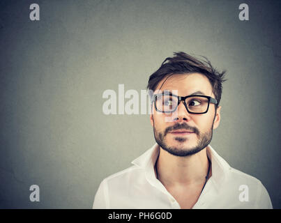 Gut aussehender bärtiger Mann, in der Kontemplation die Entscheidung auf grauem Hintergrund Stockfoto