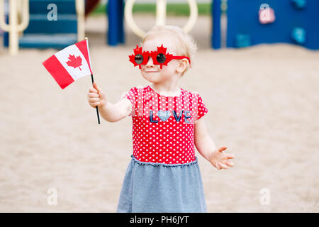 Portrait von adorable kleine süße blonde kaukasische Baby Kleinkind Mädchen, dass kanadische Flagge. Weibliches Kind tragen lustig Ahornblätter Sonnenbrille celebrat Stockfoto