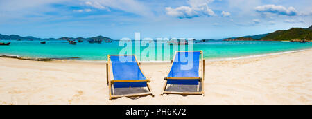 Schönen weißen Sandstrand. Stühle im Vordergrund, Fischerboote auf Hintergrund. Landschaft von Vietnam. Panorama Stockfoto