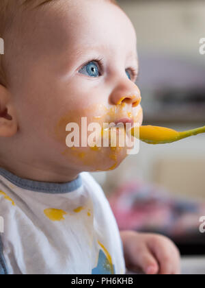 Mom feeding niedlichen kleinen Jungen mit blauen Augen schließen Stockfoto