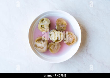 Cannned Grün Tomatenscheiben mit essiggurke Saft in Platte (die Hälfte erhalten und Gebeizt). Ökologische Lebensmittel. Stockfoto