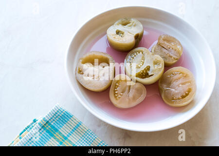 Cannned Grün Tomatenscheiben mit essiggurke Saft in Platte (die Hälfte erhalten und Gebeizt). Ökologische Lebensmittel. Stockfoto