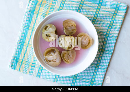 Cannned Grün Tomatenscheiben mit essiggurke Saft in Platte (die Hälfte erhalten und Gebeizt). Ökologische Lebensmittel. Stockfoto