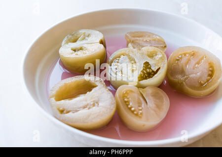 Cannned Grün Tomatenscheiben mit essiggurke Saft in Platte (die Hälfte erhalten und Gebeizt). Ökologische Lebensmittel. Stockfoto