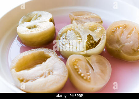 Cannned Grün Tomatenscheiben mit essiggurke Saft in Platte (die Hälfte erhalten und Gebeizt). Ökologische Lebensmittel. Stockfoto