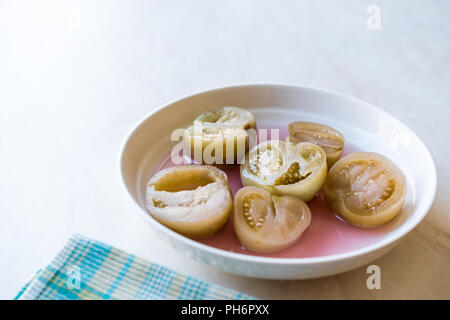 Cannned Grün Tomatenscheiben mit essiggurke Saft in Platte (die Hälfte erhalten und Gebeizt). Ökologische Lebensmittel. Stockfoto