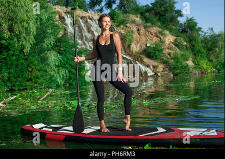 Junge athletische Frau tun Fitness auf einem Brett mit ein Ruder an einem Fluss Stockfoto