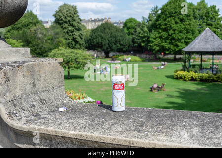 Ein kann von Stella Artois links oben auf eine Mauer um Parade Gärten mit den Musikpavillon im Hintergrund in der Stadt Bath Stockfoto