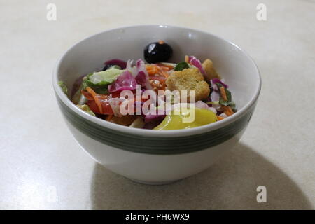 Salat in eine Schüssel geben. Stockfoto