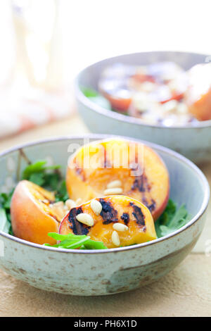 Gegrillter Pfirsich, Pinienkernen und Rucola in Schalen Stockfoto