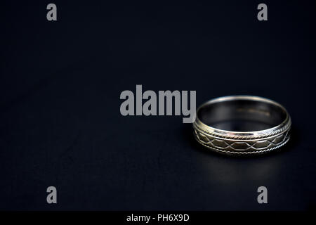 Silber handgearbeitet Hochzeit Band auf einem schwarzen Hintergrund. Zimmer für Bildunterschrift. Stockfoto