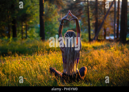 Yoga Frau auf einem malerischen Waldwiese in einem grünen Wald. Stockfoto