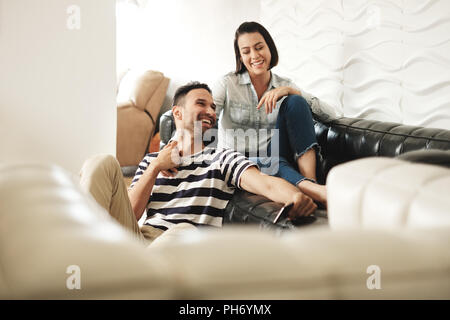 Happy Hispanic Paar mit Smartphones auf der Couch zu Hause Stockfoto