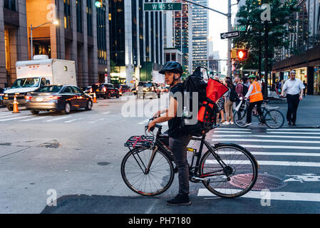 New York City, USA - 21. Juni 2018: Hispanic Kurier auf dem Fahrrad in Zebrastreifen in New York City bei Dämmerung Stockfoto